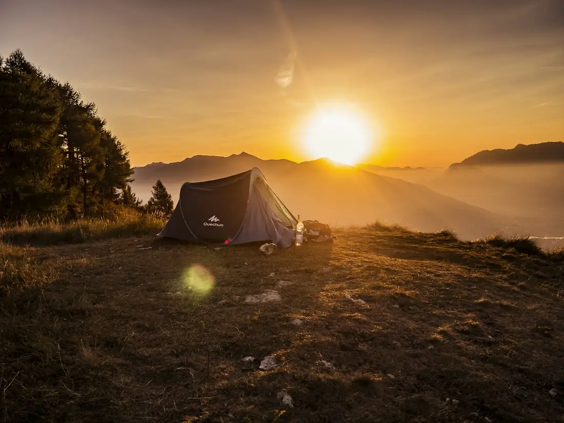 Tenda berdiri di padang rumput saat matahari terbit di atas kabut
